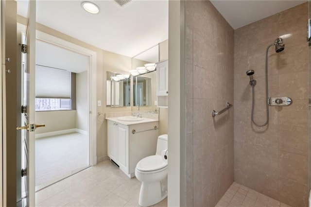 bathroom with tiled shower, toilet, vanity, tile patterned flooring, and baseboards