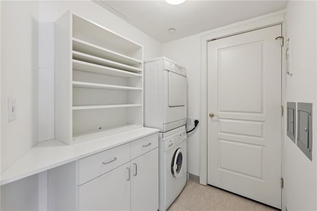 washroom featuring stacked washer / dryer and cabinet space