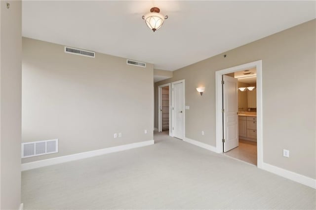 unfurnished bedroom with baseboards, light carpet, and ensuite bath
