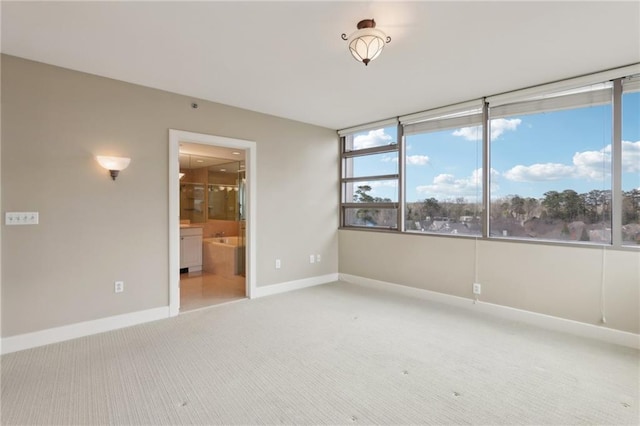 unfurnished room featuring light colored carpet and baseboards
