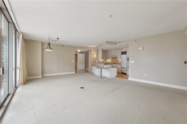 unfurnished living room featuring baseboards and light colored carpet
