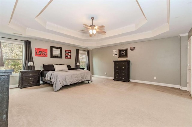 carpeted bedroom with a tray ceiling, ceiling fan, and crown molding