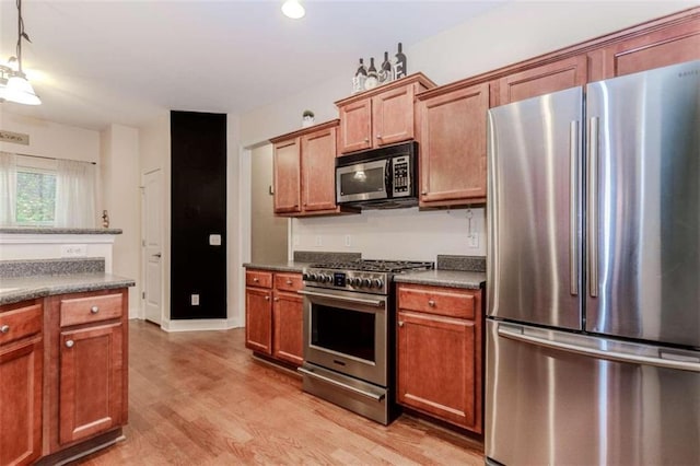 kitchen with light hardwood / wood-style floors, stainless steel appliances, and hanging light fixtures