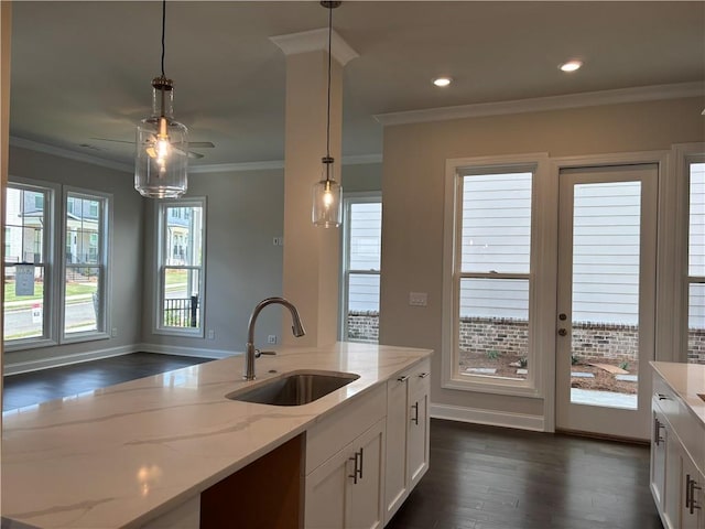 kitchen featuring a sink, dark wood finished floors, decorative light fixtures, white cabinetry, and light stone countertops