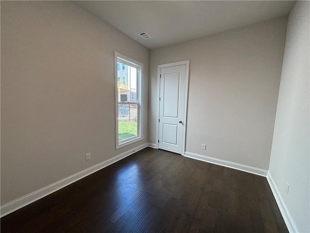 empty room featuring dark wood-style floors, plenty of natural light, and baseboards