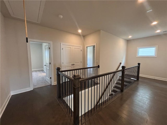 hallway featuring an upstairs landing, attic access, baseboards, dark wood-style flooring, and recessed lighting