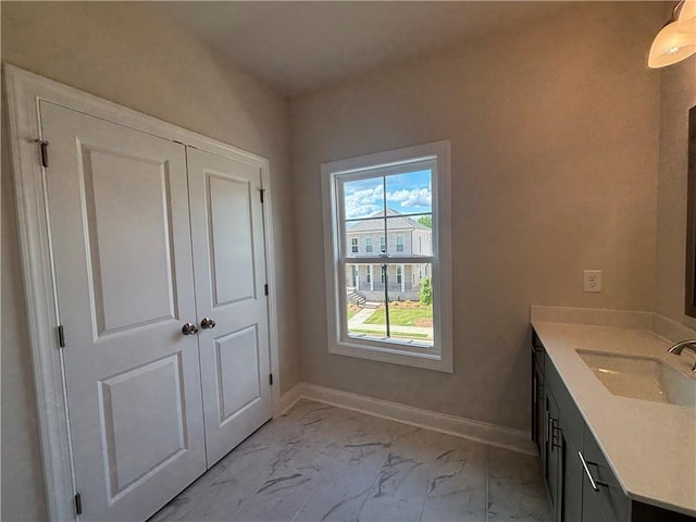 bathroom featuring marble finish flooring, vanity, and baseboards