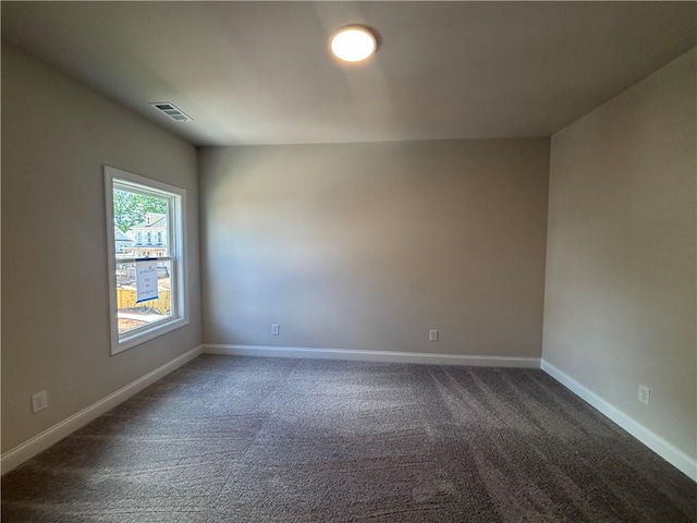 empty room with dark carpet and baseboards