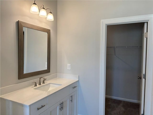 bathroom featuring vanity, a spacious closet, and baseboards