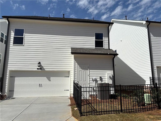 back of house with fence, a garage, concrete driveway, and central AC