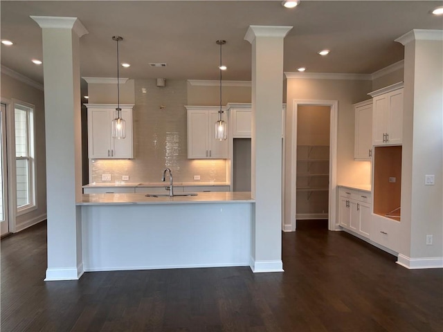 kitchen featuring a sink, decorative backsplash, baseboards, white cabinets, and crown molding