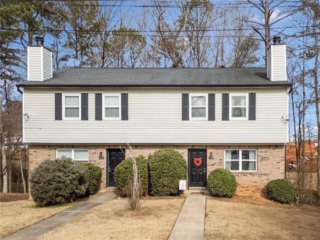 colonial home featuring brick siding and a chimney