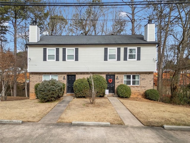 view of front of home featuring brick siding and a chimney