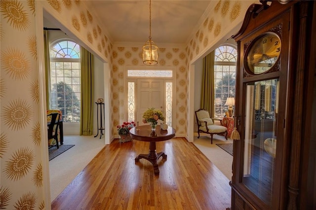 foyer entrance featuring a healthy amount of sunlight, light wood-type flooring, and ornamental molding