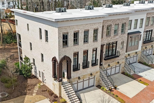 view of building exterior featuring a garage, stairs, central air condition unit, and driveway