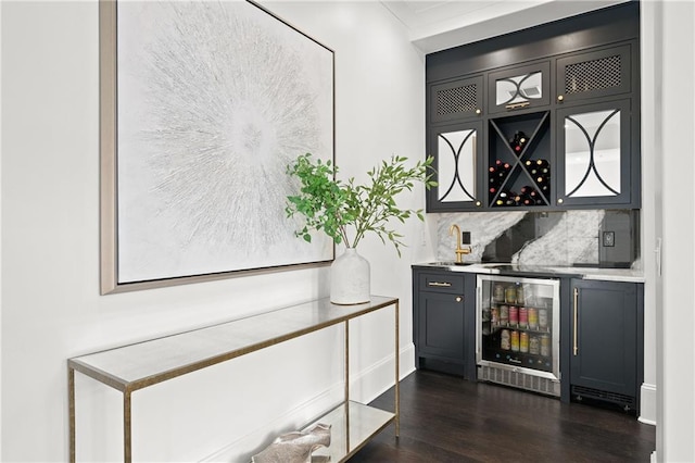 bar featuring beverage cooler, dark wood-style floors, wet bar, and tasteful backsplash