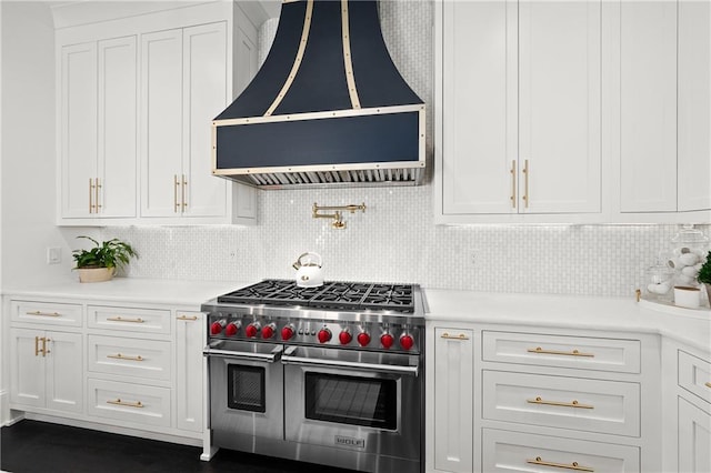 kitchen with backsplash, premium range hood, light countertops, range with two ovens, and white cabinets