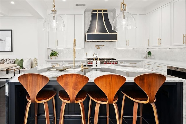 kitchen with tasteful backsplash, visible vents, light stone countertops, white cabinets, and wall chimney exhaust hood