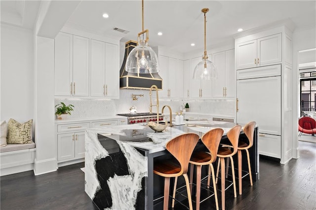 kitchen with paneled built in fridge, white cabinets, visible vents, and backsplash