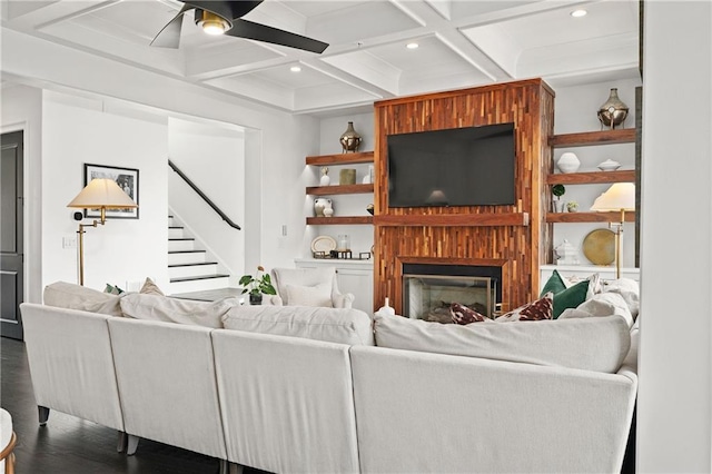 living room featuring stairs, beam ceiling, wood finished floors, coffered ceiling, and a ceiling fan