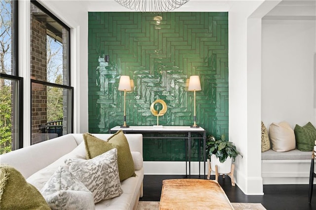 living area featuring wallpapered walls, baseboards, wood finished floors, and an accent wall