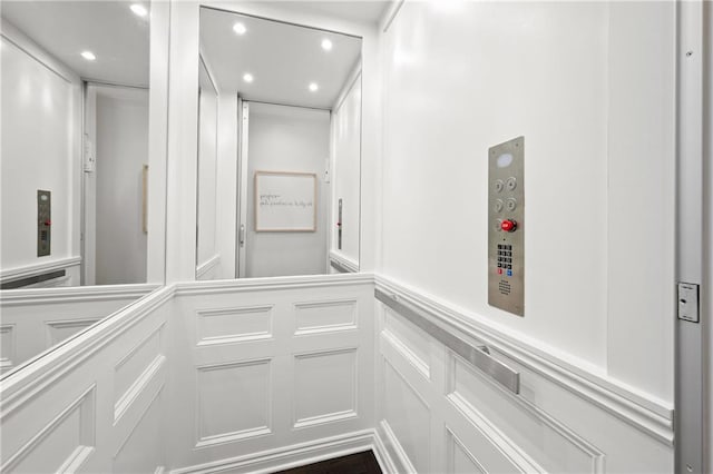 interior details featuring recessed lighting, elevator, wainscoting, and a decorative wall