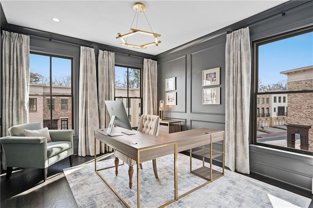 office with a notable chandelier, wood finished floors, and a decorative wall