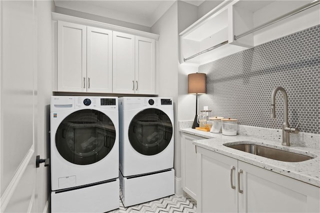 clothes washing area with a sink, cabinet space, and washing machine and clothes dryer