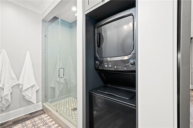 bathroom with a stall shower, stacked washing maching and dryer, and wood finished floors