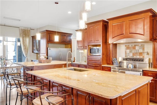 kitchen with decorative backsplash, appliances with stainless steel finishes, a breakfast bar area, a kitchen island with sink, and a sink