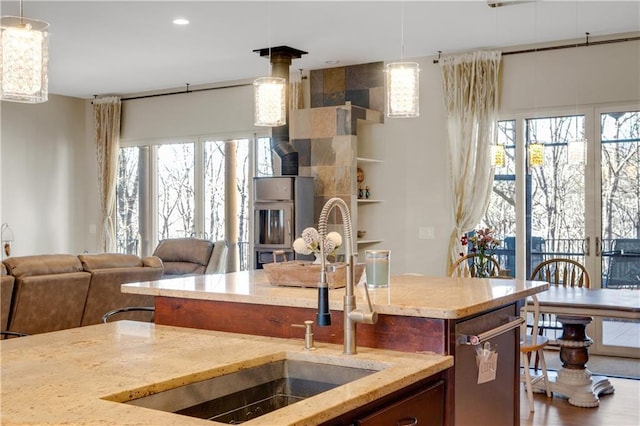 kitchen with a wood stove, plenty of natural light, light stone counters, and a sink