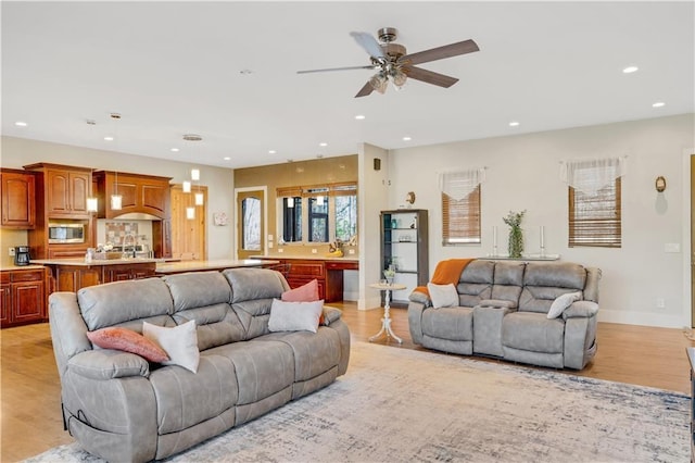 living area with light wood-style floors, ceiling fan, baseboards, and recessed lighting