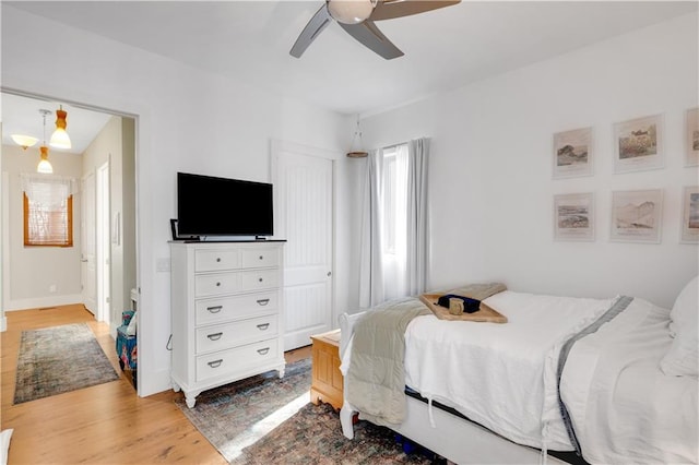 bedroom with a ceiling fan, baseboards, and light wood finished floors