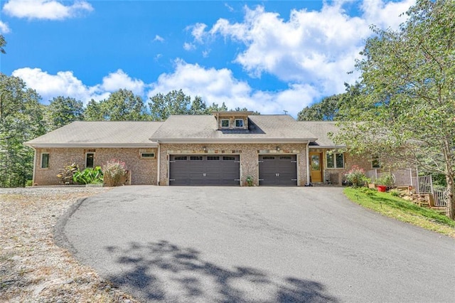 view of front facade featuring aphalt driveway, brick siding, and an attached garage