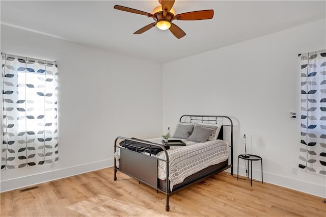 bedroom with baseboards, ceiling fan, and light wood-style floors