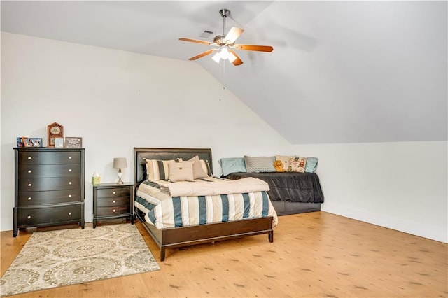 bedroom with wood finished floors, visible vents, baseboards, vaulted ceiling, and a ceiling fan