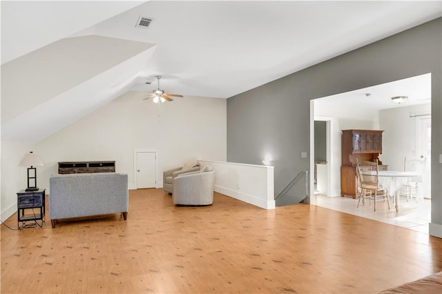 sitting room with lofted ceiling, light wood-style floors, visible vents, and an upstairs landing