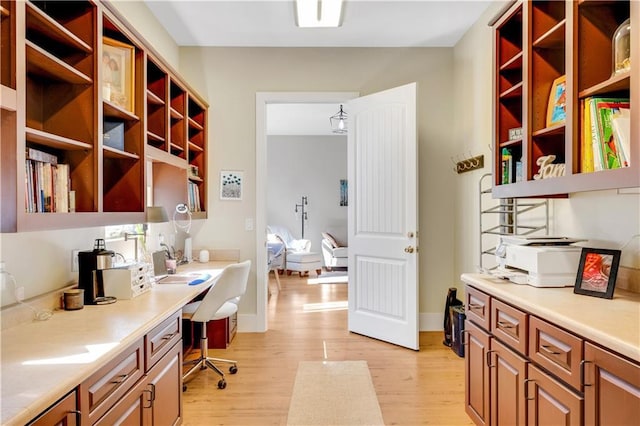 office featuring light wood-type flooring, built in study area, and baseboards