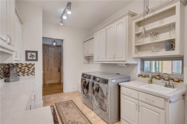 clothes washing area featuring light tile patterned floors, cabinet space, washing machine and dryer, a sink, and baseboards