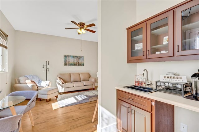 interior space with light wood-type flooring, a ceiling fan, and a sink