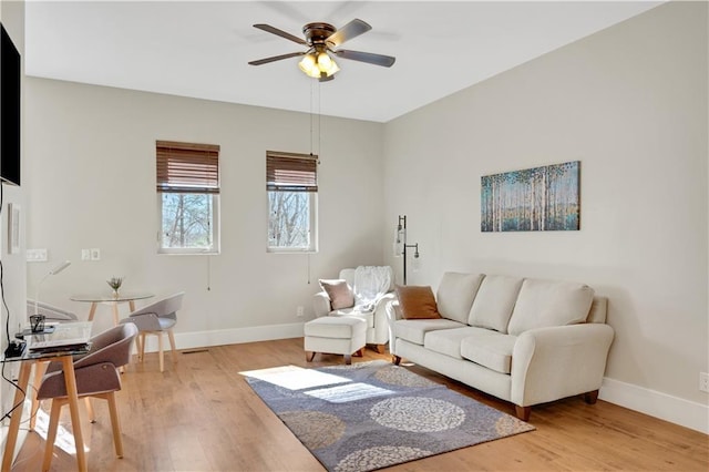 living room featuring light wood-style flooring, baseboards, and ceiling fan