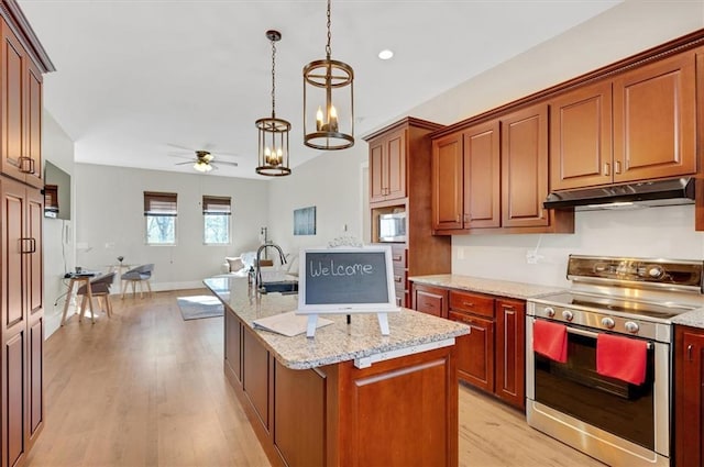 kitchen featuring light wood finished floors, a ceiling fan, appliances with stainless steel finishes, open floor plan, and under cabinet range hood