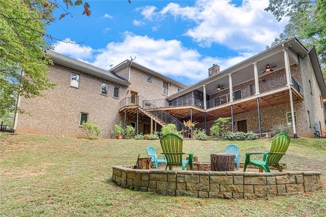 rear view of house with an outdoor fire pit, a lawn, a ceiling fan, a chimney, and stairway