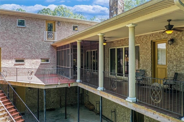 back of house featuring a sunroom, brick siding, ceiling fan, and stairway