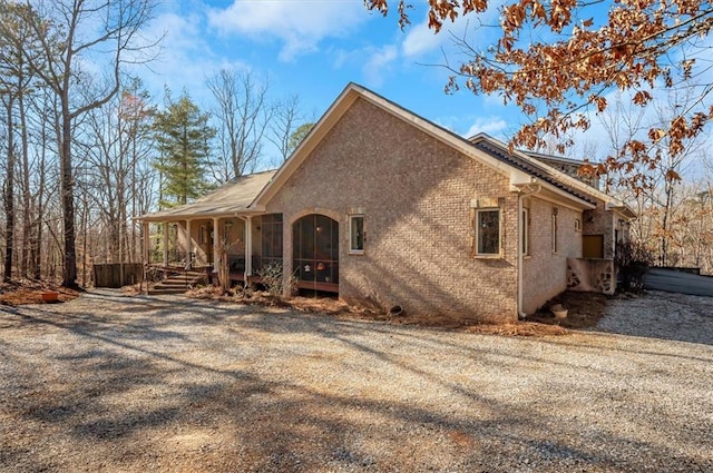 view of side of home with a porch and brick siding