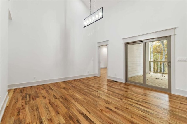 unfurnished room featuring a high ceiling, baseboards, and wood finished floors