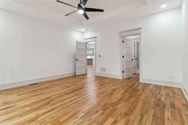 unfurnished bedroom with recessed lighting, a raised ceiling, visible vents, light wood-style floors, and baseboards