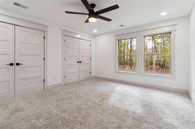 unfurnished bedroom featuring carpet, two closets, visible vents, and baseboards