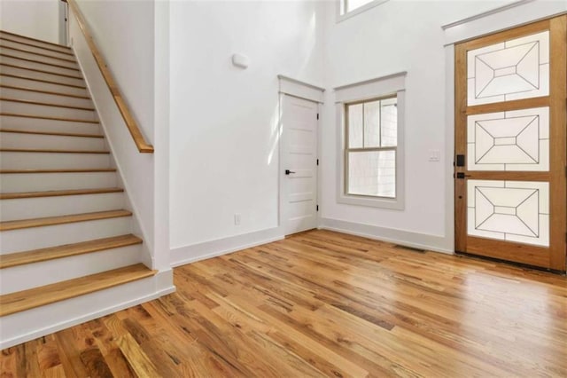 foyer with stairs, light wood finished floors, visible vents, and baseboards