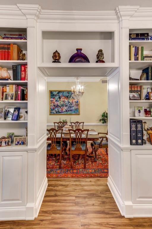 dining room featuring hardwood / wood-style floors, built in features, and a notable chandelier